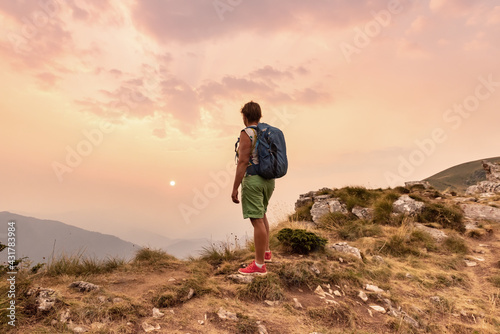 One tourist with backpacks enjoying sunset on top of a mountain