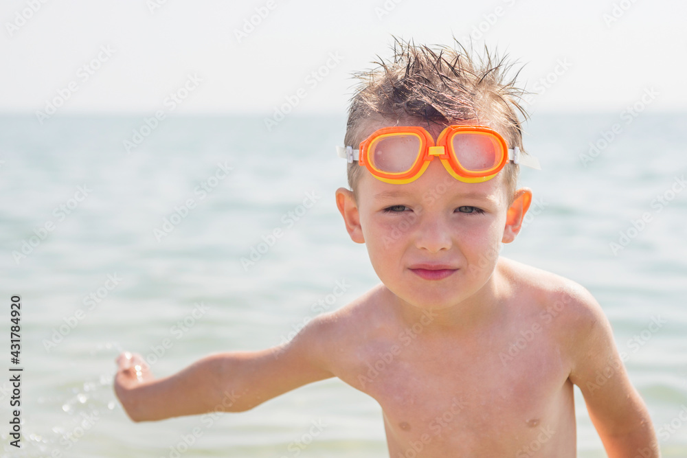 Naklejka premium Portrait of a cheerful boy in goggles for swimming while relaxing on the sea. Summer vacation