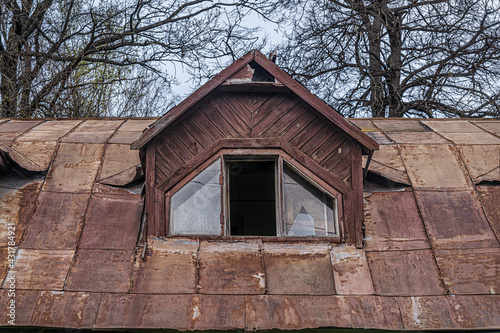 rusty roof and broken window in the attic of an abandoned wooden house © Mariia