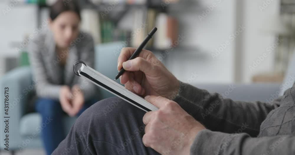 Professional therapist listening to the patient and writing notes
