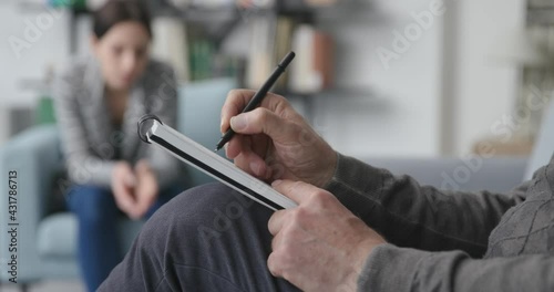 Professional therapist listening to the patient and writing notes photo