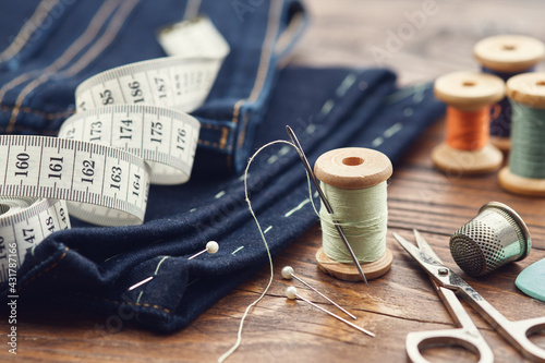 Shortening jeans. Measuring tape, scissors, spools of thread, thimble, including pins and chalk. Jeans cutting. photo