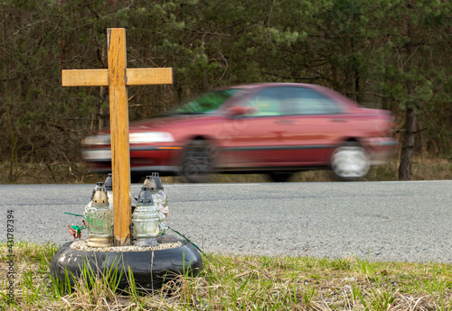 A roadside memorial cross with a candles commemorating the tragic death, on a background ride blurred car. photo