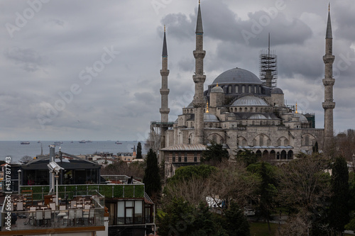 The Blue Mosque in Istanbul is located on Sultanahmet Square. It is made of gray stone, has high minarets. The photo was taken against the background of a sea shore on a cloudy day with dramatic sky 