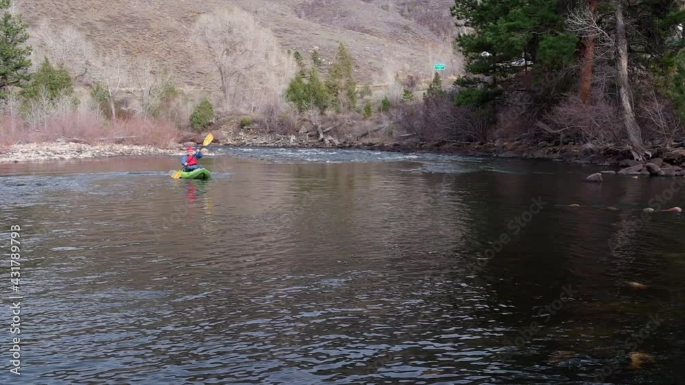 senior male kayaker is paddling an inflatable whitewater kayak on a mountain river - Poudre River in the canyon above Fort Collins, Colorado, in early spring scenery senior male kayaker is paddling an inflatable whitewater kayak on a mountain river - Poudre River in the canyon above Fort Collins, Colorado, in early spring scenery