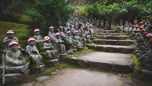 Buddha statues with knitted hat offerings along shrine path at the temple Diasho-in in Miyajima, Hiroshima, Japan