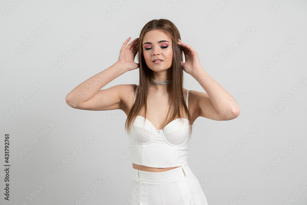 Stylish, well-groomed, young woman posing on a brown background. Lady touches her hair isolated on the background of an empty wall Stylish, well-groomed, young woman posing on a brown background. Lady touches her hair isolated on the background of an empty wall