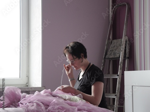 The girl sews purple fabric. Housework. Do-it-yourself apartment renovation. Interior textiles. 