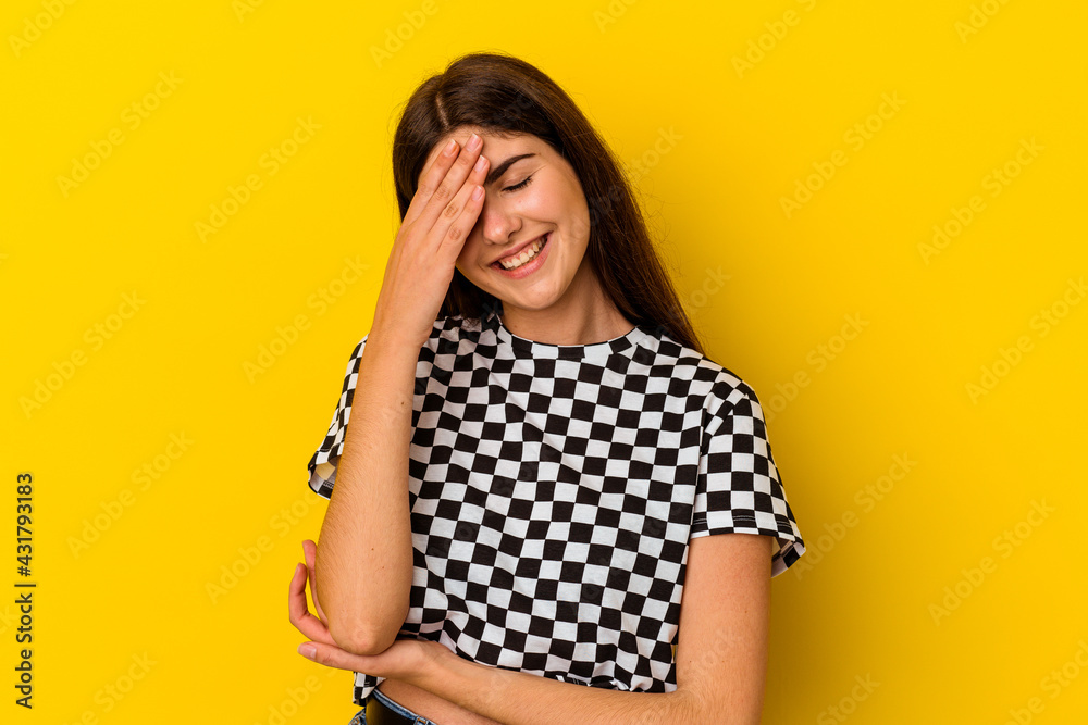Young caucasian woman isolated on yellow background blink at the camera through fingers, embarrassed covering face. Young caucasian woman isolated on yellow background blink at the camera through fingers, embarrassed covering face.