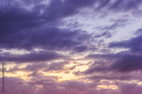 Sunset sky with clouds and sunbeams through wind clouds.