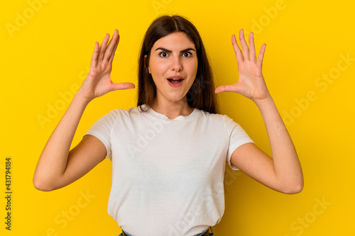 Young caucasian woman isolated on yellow background celebrating a victory or success, he is surprised and shocked.