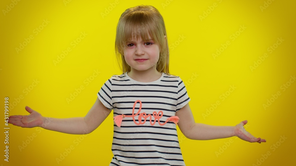 Confused mad blonde child girl raising hands in indignant expression, asking why, what reason of failure, demonstrating disbelief irritation by troubles on yellow wall background. Teen kid children