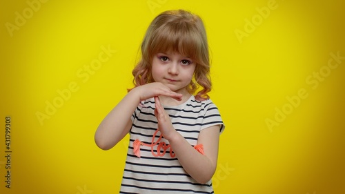 Portrait of serious blonde child girl 5-6 years old in striped t-shirt showing time out gesture, limit or stop sign, no pressure, i need more time on yellow studio wall background. Teen kid children