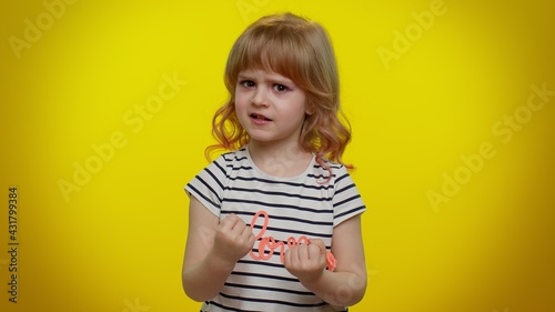 Aggressive angry blonde kid child 5-6 years old in t-shirt trying to fight at camera, shaking fist, boxing with expression, punishment on yellow studio background. Teenager children girl emotions
