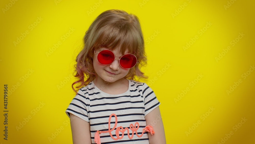 Portrait of seductive funny playful blonde kid child 5-6 years old wearing sunglasses, looking at camera with charming smile. Stylish teenager children girl on yellow studio background Portrait of seductive funny playful blonde kid child 5-6 years old wearing sunglasses, looking at camera with charming smile. Stylish teenager children girl on yellow studio background