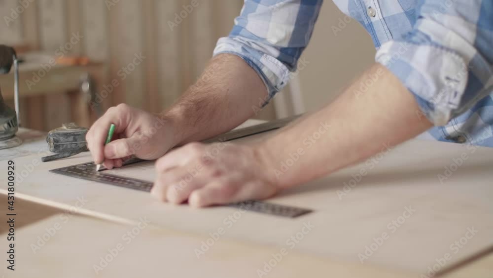 Carpenter makes pencil markings on the blank with the help of a ruler Carpenter makes pencil markings on the blank with the help of a ruler
