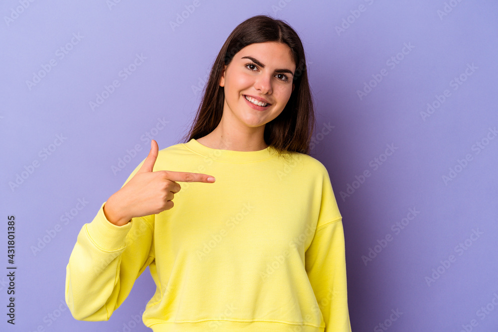 Young caucasian woman isolated on purple background person pointing by hand to a shirt copy space, proud and confident Young caucasian woman isolated on purple background person pointing by hand to a shirt copy space, proud and confident