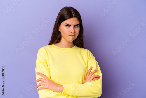 Young caucasian woman isolated on purple background frowning face in displeasure, keeps arms folded.