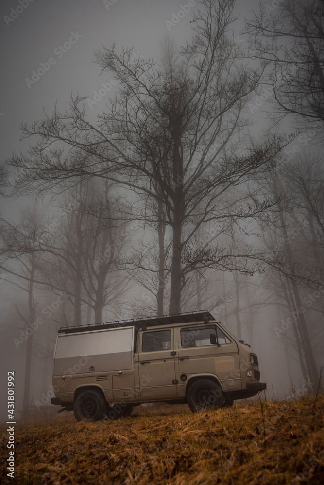 Vintage adventure campervan parked in a misty forest, adventourous and scary mission to discover new worlds with an old van