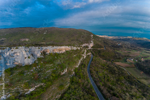 Aerial drone view of Veli Badin, natural stone cliff carved in the rock overlapping the ground, during a sunny afternoon. Majestic rock structure in slovenian Karst.