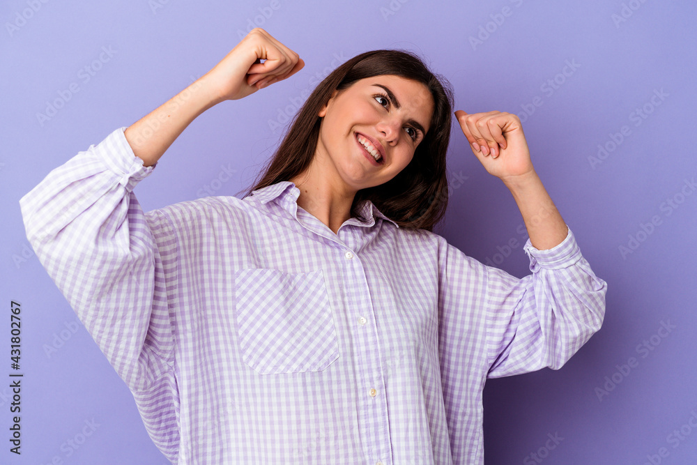 Young caucasian woman isolated on purple background celebrating a special day, jumps and raise arms with energy. Young caucasian woman isolated on purple background celebrating a special day, jumps and raise arms with energy.