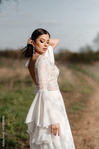 A beautiful bride in a light dress poses. Boho style. 