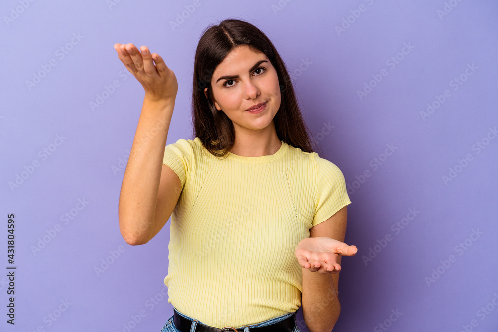 Young caucasian woman isolated on purple background makes scale with arms, feels happy and confident. Young caucasian woman isolated on purple background makes scale with arms, feels happy and confident.