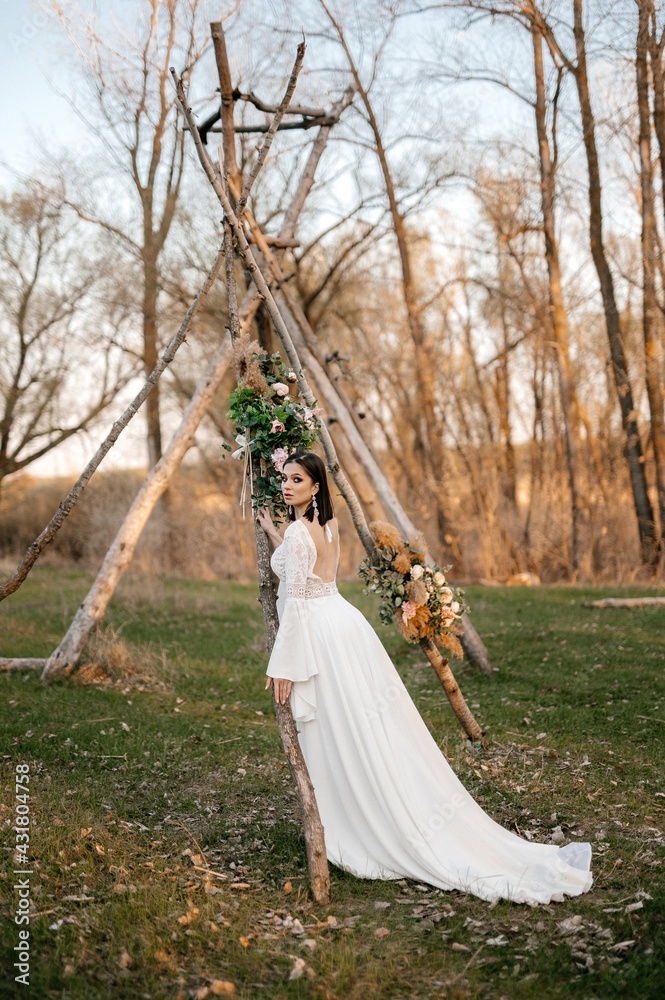 A beautiful bride in a light dress poses. Boho style. A beautiful bride in a light dress poses. Boho style.