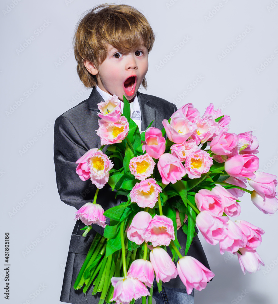 Surprised little boy with bouquet of tulips. Stylish child in elegant suit with flowers. Birthday, Women's Day, Mother's Day, Valentines day. Surprised little boy with bouquet of tulips. Stylish child in elegant suit with flowers. Birthday, Women's Day, Mother's Day, Valentines day.