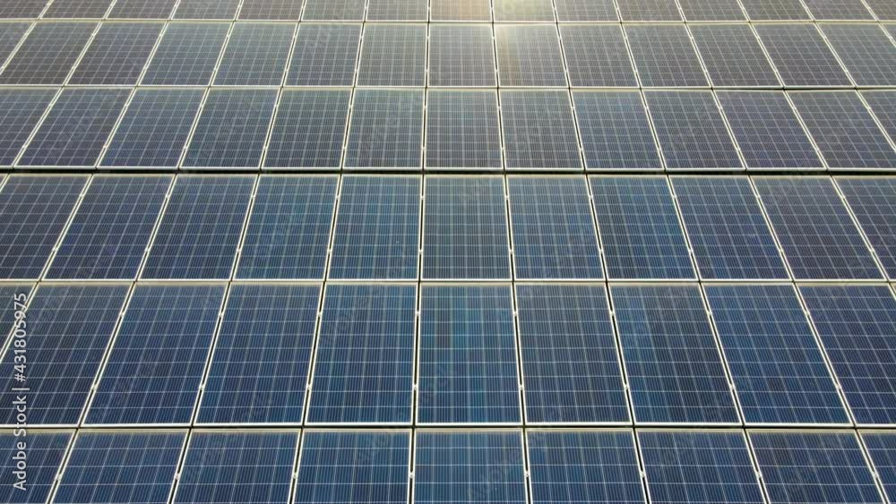 Aerial view of surface of blue photovoltaic solar panels mounted on building roof for producing clean ecological electricity. Production of renewable energy concept.