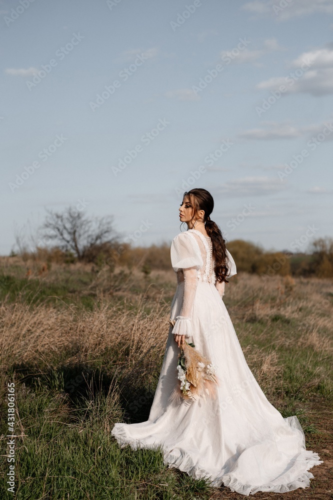 A beautiful bride in a light dress poses. Boho style.