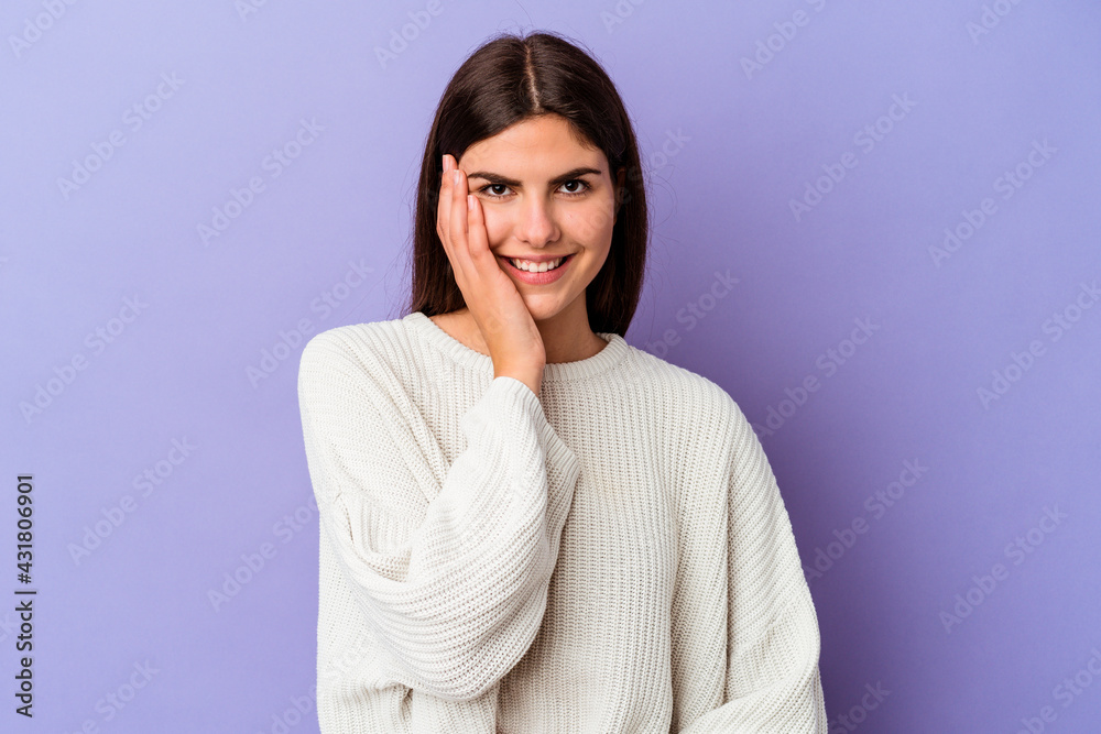 Young caucasian woman isolated on purple background laughs happily and has fun keeping hands on stomach. Young caucasian woman isolated on purple background laughs happily and has fun keeping hands on stomach.