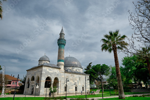 Bursa, Turkey. Green mosque (yesil camii) in Nicaea (iznik) during spring and sunny day in center of the city covered by many green plants, and palm trees and it turquoise color minaret photo