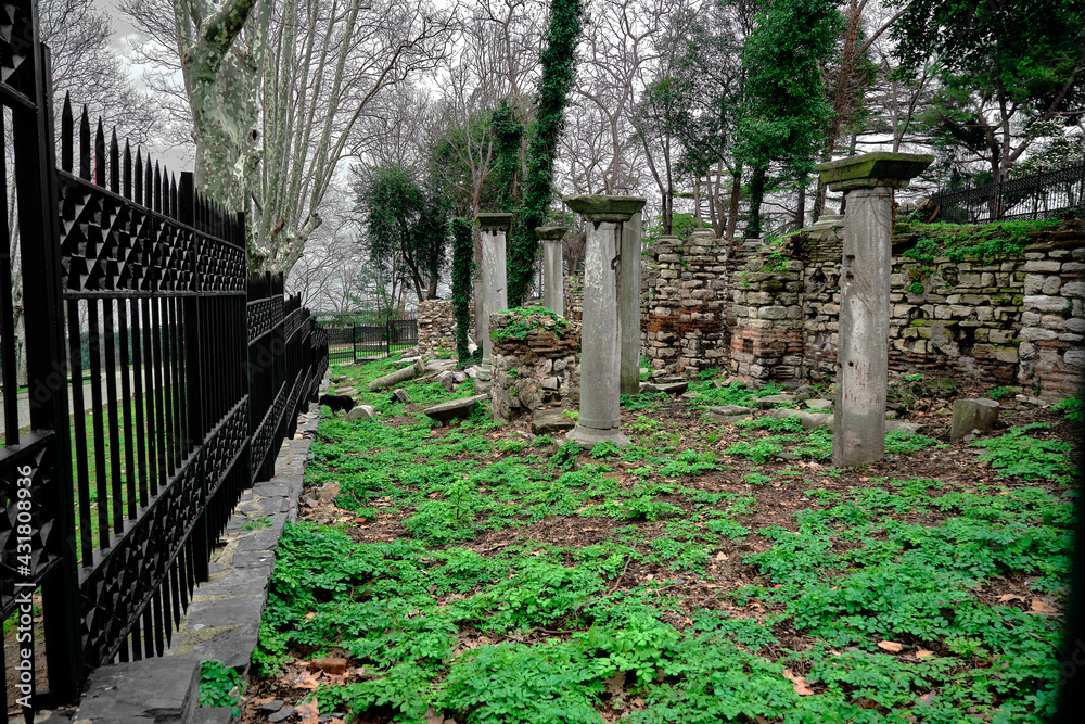 Old remainings and ruins from byzantium in covered by metal and black fences. There are many green plants and greens around the roman ruins in istanbul gulhane park during overcast and rainy day. Old remainings and ruins from byzantium in covered by metal and black fences. There are many green plants and greens around the roman ruins in istanbul gulhane park during overcast and rainy day.