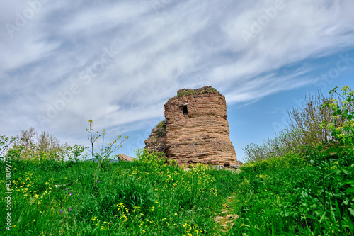 Old and ancient city wall in nicaea (iznik Bursa) established by Byzantium with ruin and stones graves with many green grass and yellow flowers during sunny day and small pathway along the huge grass. photo