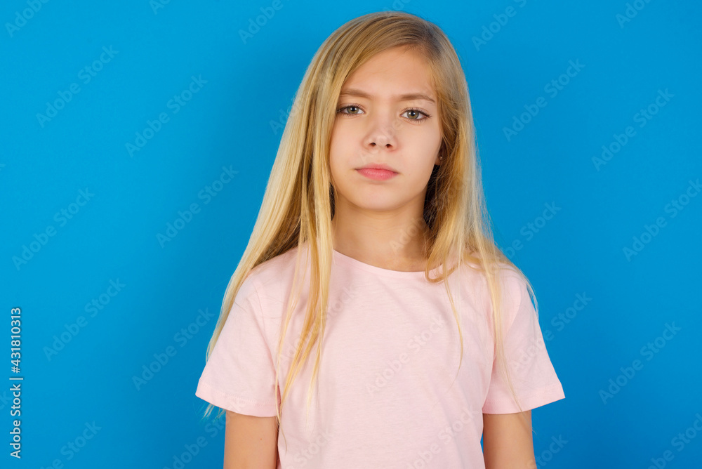 Caucasian kid girl wearing pink shirt against blue wall Pointing down with fingers showing advertisement, surprised face and open mouth Caucasian kid girl wearing pink shirt against blue wall Pointing down with fingers showing advertisement, surprised face and open mouth