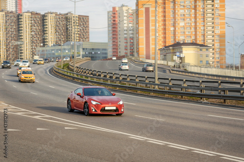 The car is driving on a high-speed wide highway. Behind you can see the multi-storey buildings of a large city