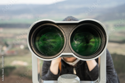 young man watching with a binocular, tactical spying outdoors