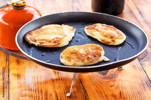 three pancakes fried in a pan and a tourist burner at a camping