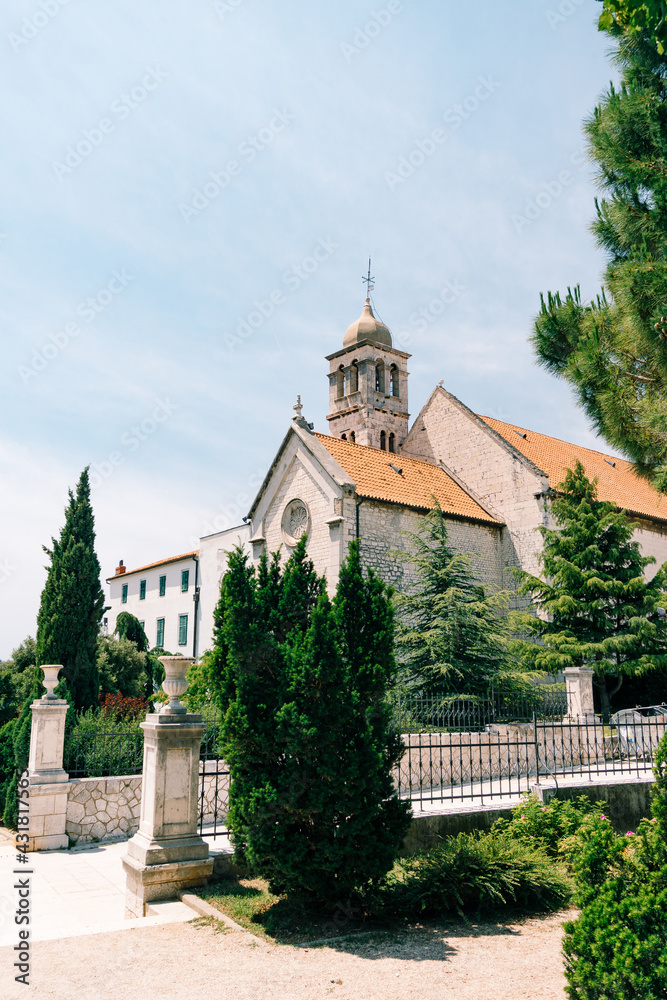 Entrance to the Monastery of St. Franz in Sibenik against the background of blue sky and green trees