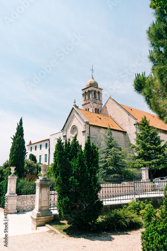 Entrance to the Monastery of St. Franz in Sibenik against the background of blue sky and green trees