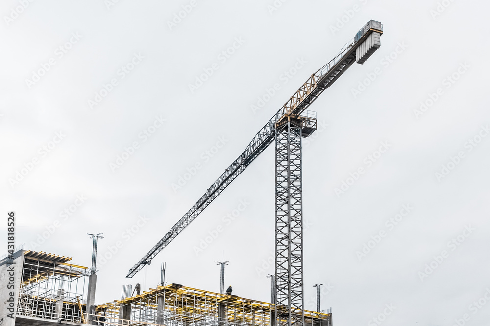 Industrial tower crane builds new concrete city building or apartments on construction site