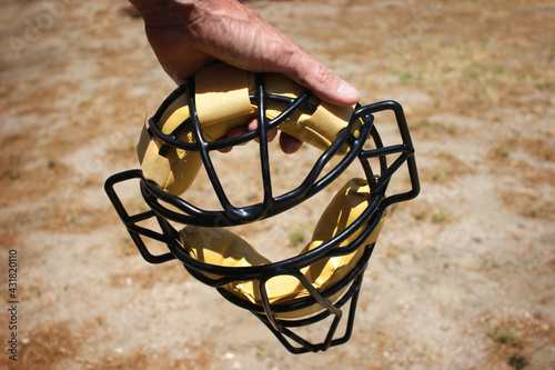 Baseball protective mask being held by player