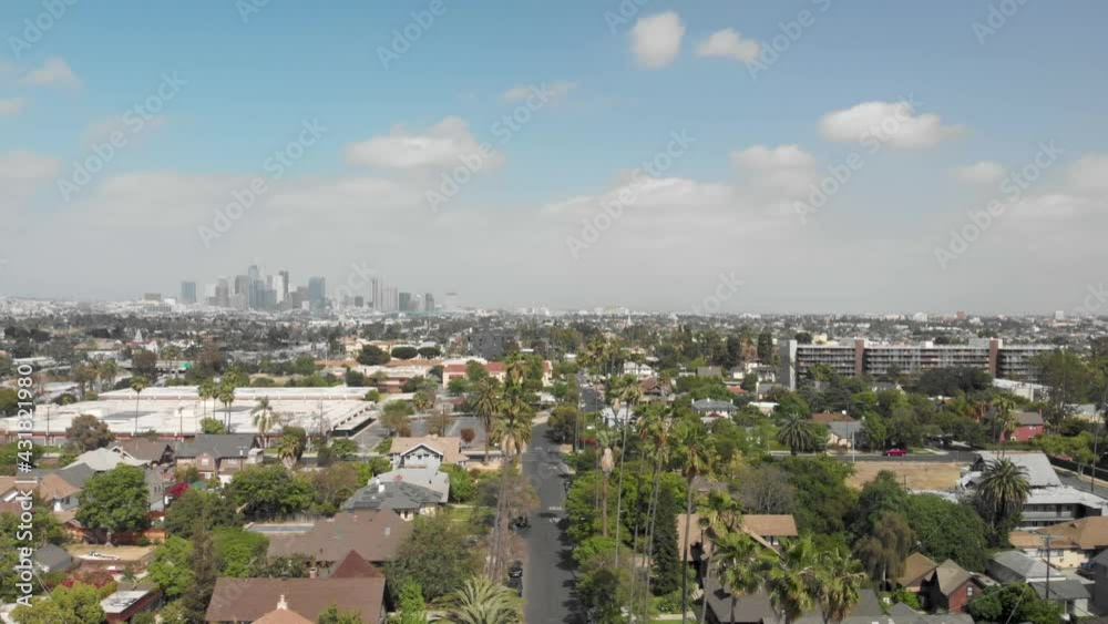 Aerial flying over a neighborhood in Los Angeles over palm trees with downtown Los Angels in the background, on a sunny windy day, California, USA Aerial flying over a neighborhood in Los Angeles over palm trees with downtown Los Angels in the background, on a sunny windy day, California, USA