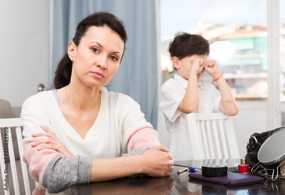 Fototapeta premium Upset woman sitting and looking away after quarrel with her teenage son..