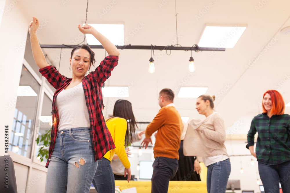 Fototapeta premium Team of successful multiethnic coworkers in modern office workplace dancing and celebrating success. Diversity happines concept