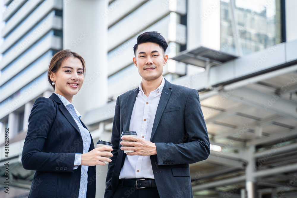 Asian young business people standing in the city, holding coffee cup. Asian young business people standing in the city, holding coffee cup.