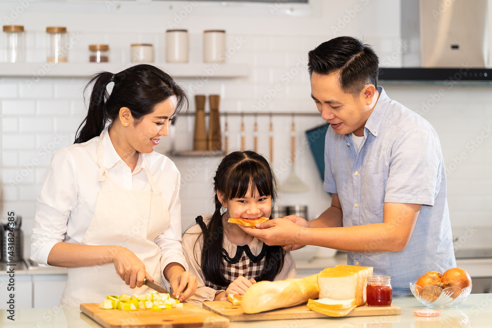 Asian family cooking food in the kitchen, father feeding bread to kid. Asian family cooking food in the kitchen, father feeding bread to kid.