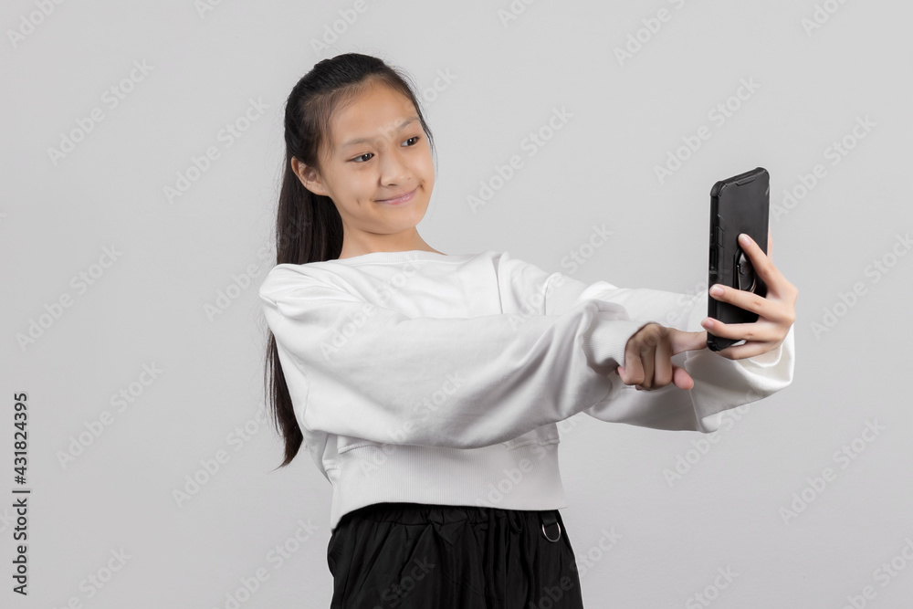 Cute little girl taking selfie with mobile phone on gray background Cute little girl taking selfie with mobile phone on gray background
