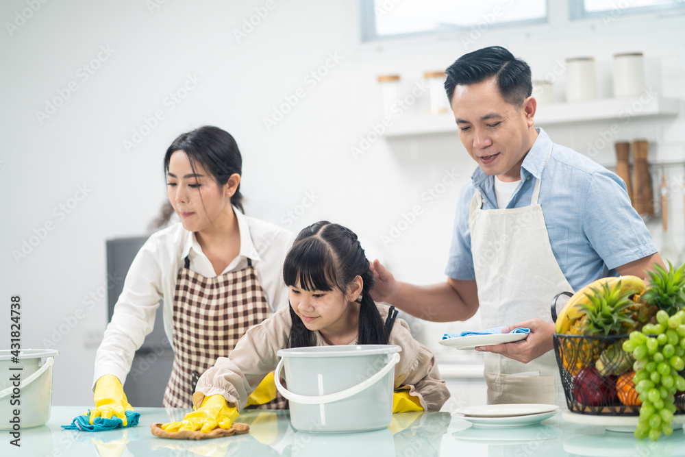 Asian young family teaching their daughter to clean kitchen counter. Asian young family teaching their daughter to clean kitchen counter.